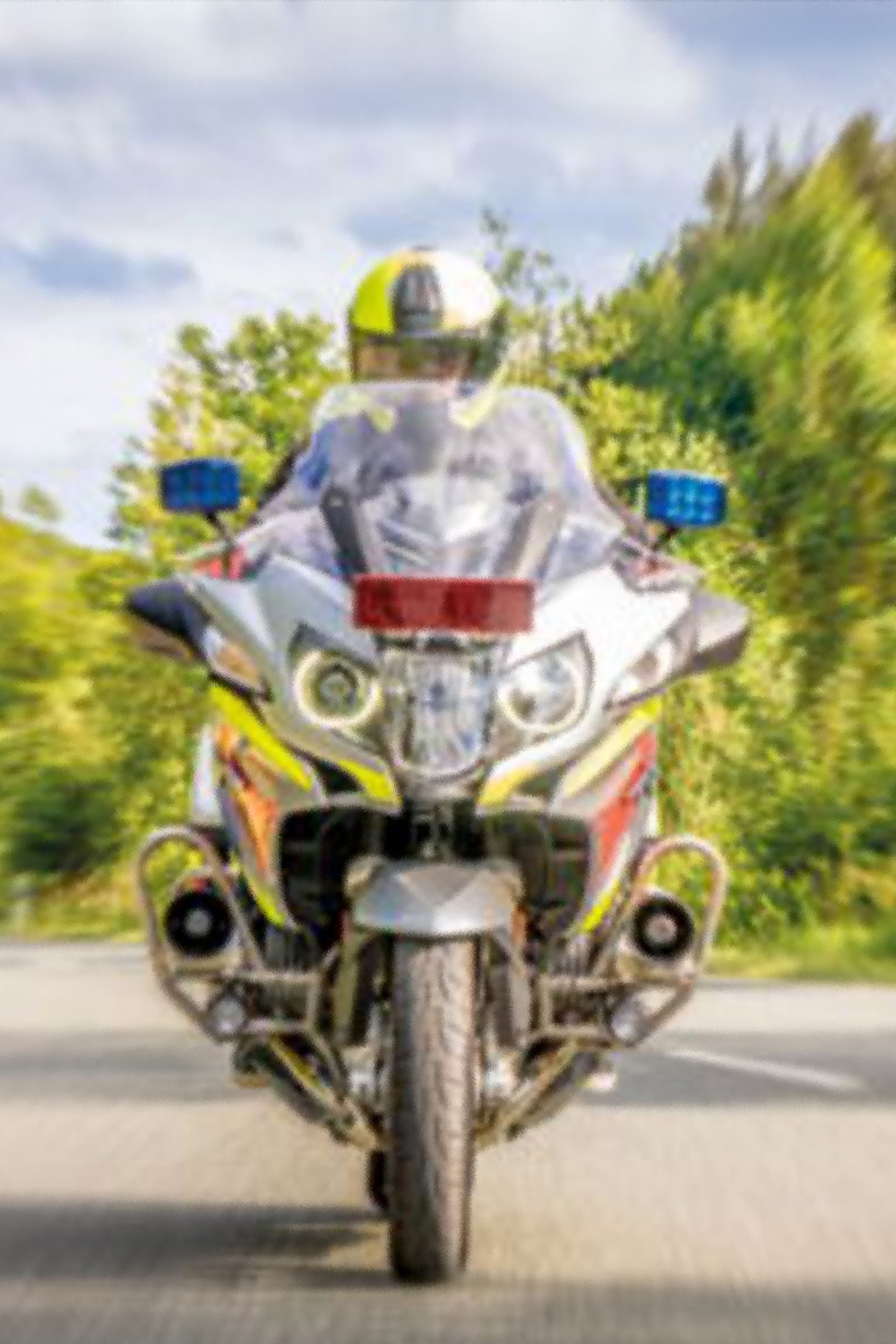 Rettungsmotorrad mit Blaulicht fährt auf einer Landstraße auf die Kamera zu