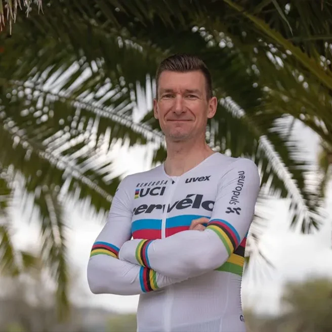Marken-Botschafter Matthias Schindler steht im Rennrad-Outfit mit verschränkten Armen vor einer Palme